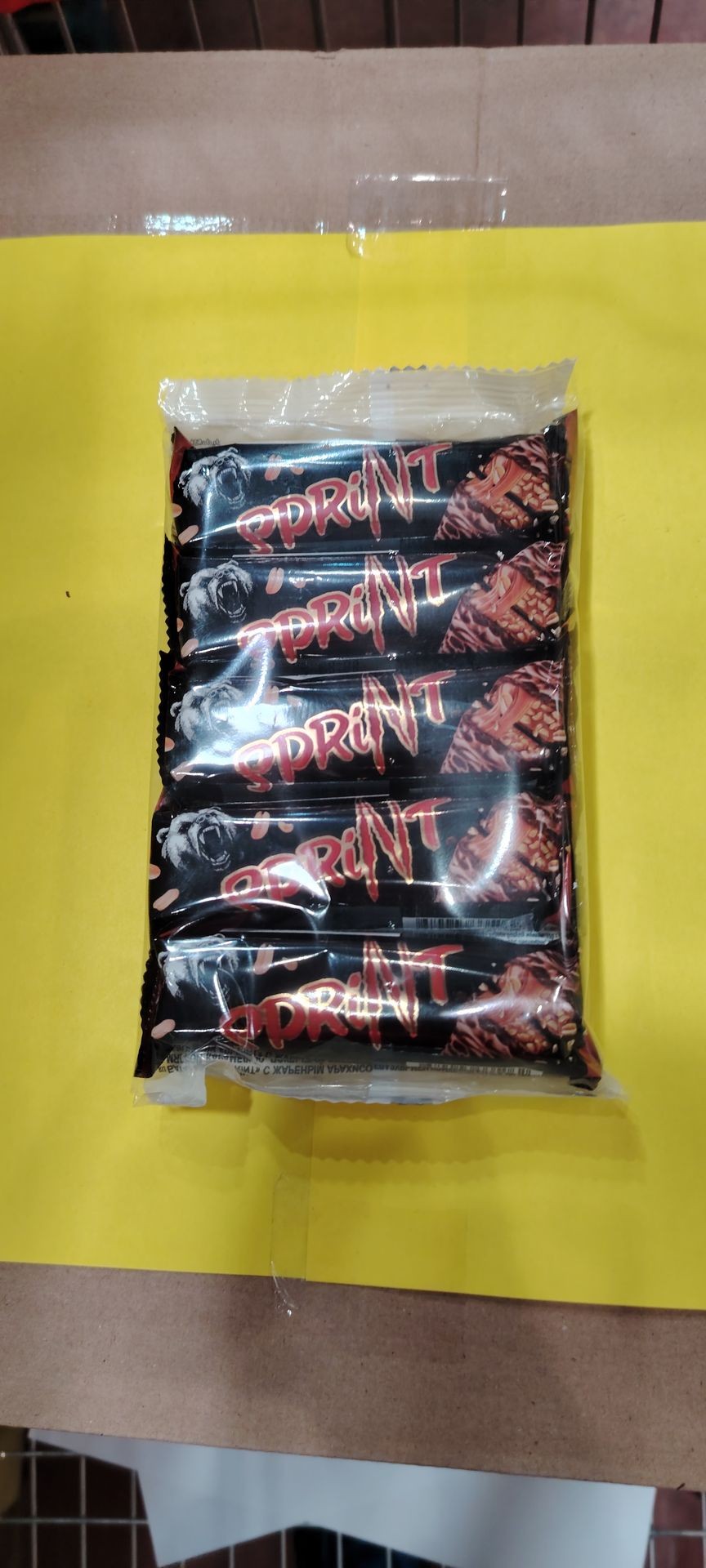 Six-pack of chocolate bars labeled 'Sprint' in a plastic package on a yellow background.